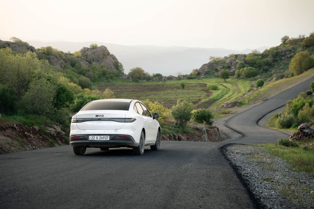 pexels-photo-37822522-37822522-1 A white car drives on a winding road through scenic hills in Shaqlawa, Iraq during daylight.